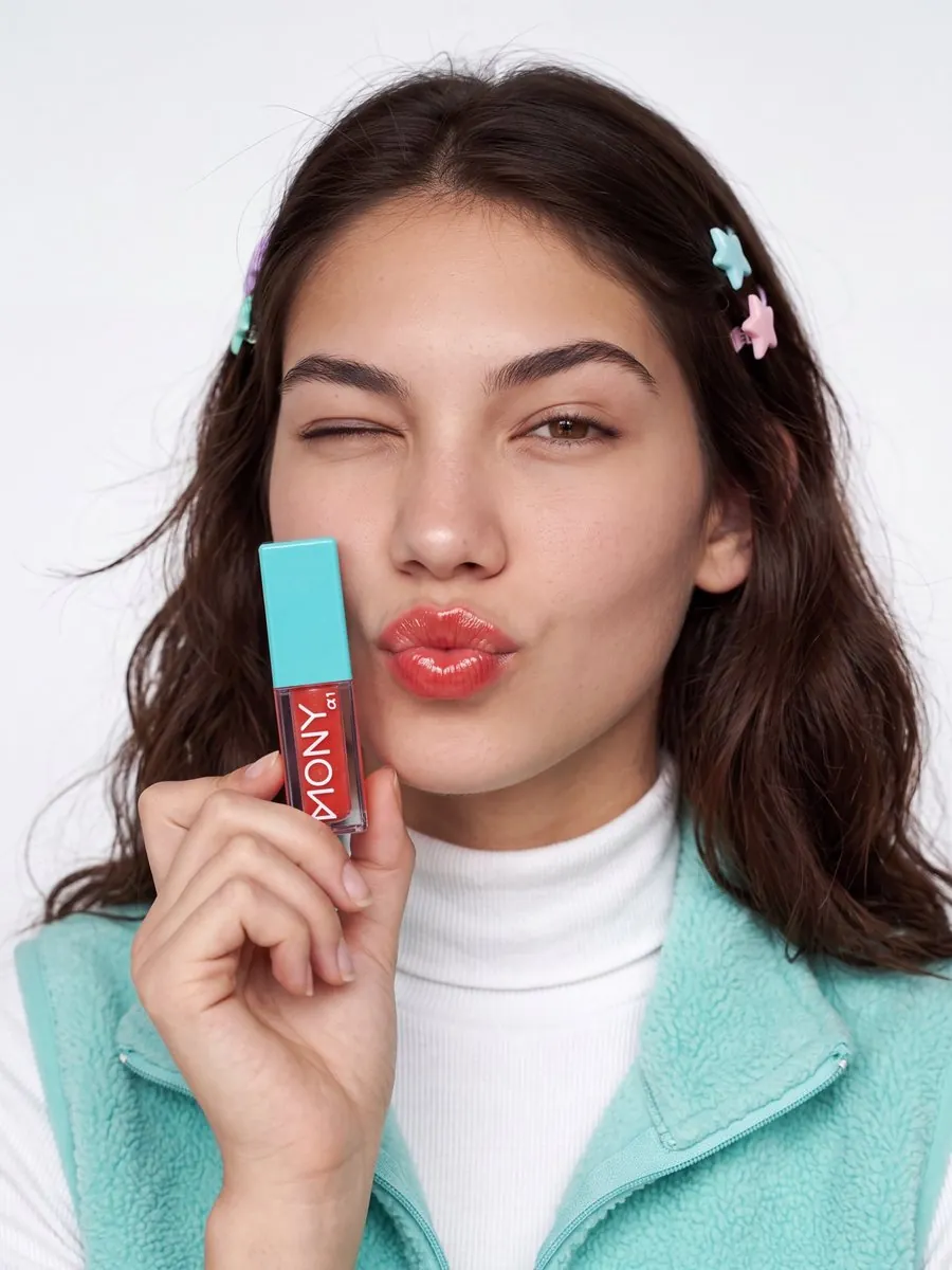 Beauty category: model holding a lip gloss and blowing a kiss