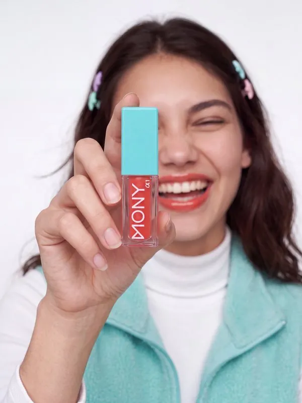 Beauty category: smiling model holding up a lip gloss